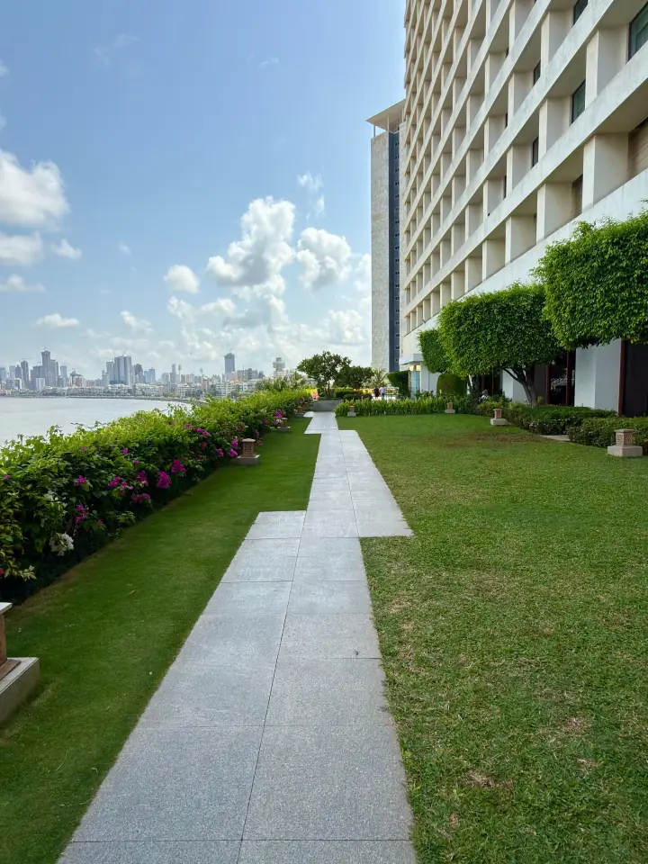 Riverside condominium grounds: clipped lawns, a long paver walk and flowering hedges along the water